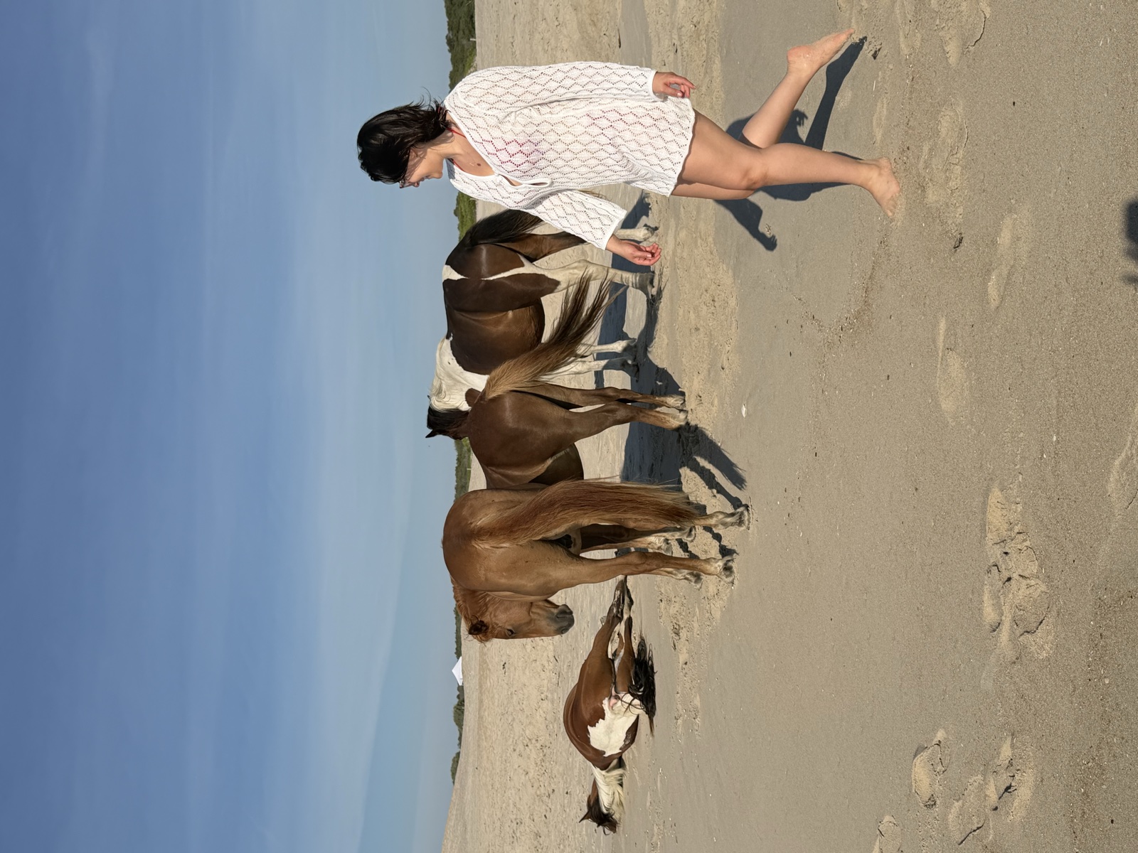 Mujer caminando en la playa junto a caballos — foto real