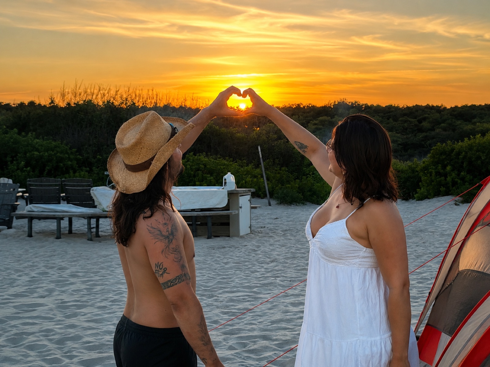 Pareja formando un corazón con las manos frente al atardecer — foto real